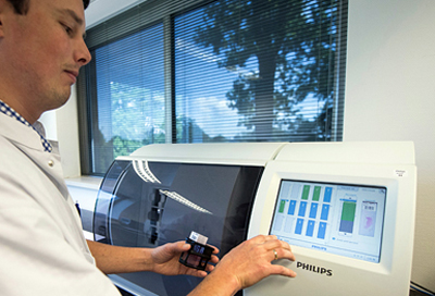 Quick turnaround: a technician inserts tissue slides into Philips IntelliSite ultra-fast scanner.