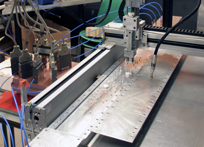 Experimental setup of the random anti-laser: a waveguide contains a disordered medium consisting of a set of randomly placed Teflon cylinders, at which incoming microwave signals are scattered in a complex manner. In the top plate of the waveguide (moved aside for illustrative purposes) a central antenna is installed, which absorbs the microwaves. Image: TUV.