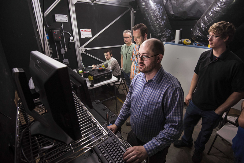 The research team reviews data coming in from a test in Sandia National Laboratories' fog chamber. This photo was taken prior to the COVID-19 pandemic. Photo: Randy Montoya / SNL.