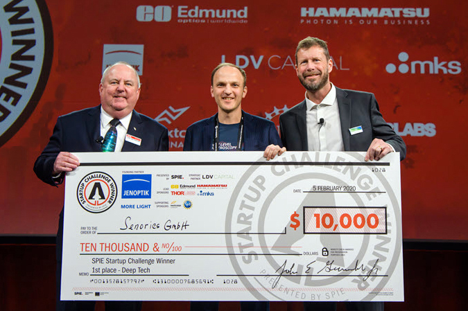 <cap>CEO of Senorics Ronny Timmreck, center, receives the first-place prize in the 2020 SPIE Startup Challenge from then-SPIE President John Greivenkamp, left, and Jenoptik Optical Systems President Jay Kumler.