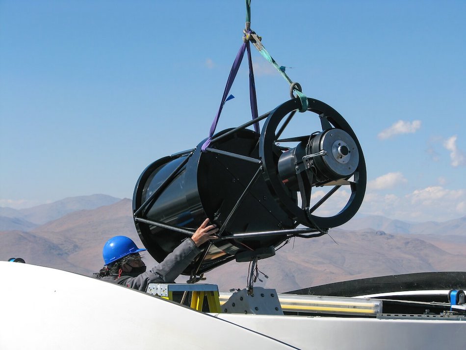 An engineer guides the telescope structure of the Test-Bed Telescope 2 carefully into place as it is lowered into its sheltering dome at ESO's La Silla Observatory. Credit: P. Sinclaire/ESO
