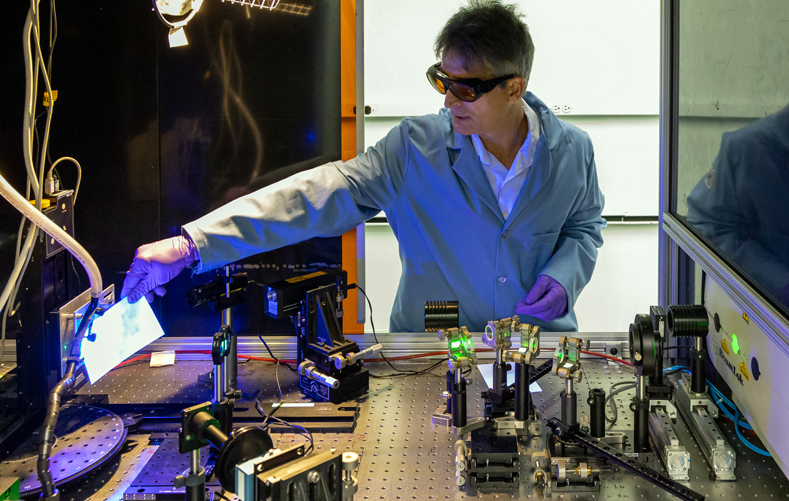 ORNL scientist Adrian Sabau describes components of a laser-interference structuring system that was used to treat aluminum alloy sheets for corrosion protection. Credit: Carlos Jones/ORNL, U.S. Dept. of Energy.