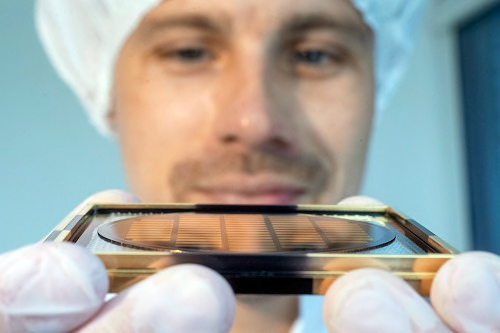 A Q.ANT employee holds up a wafer from which photonic chips are cut. Credit: Q.ANT GmbH. 