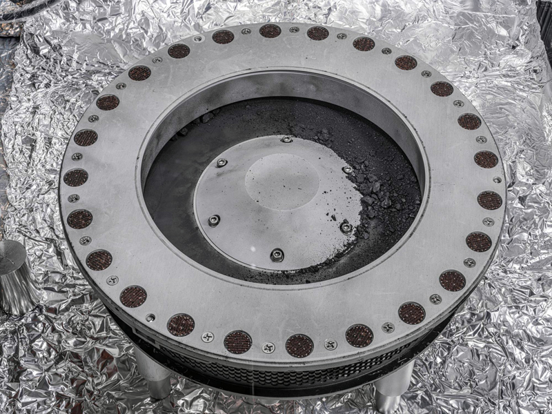 A view of the outside of the OSIRIS-REx sample collector. Sample material from asteroid Bennu can be seen on the middle right. Scientists have found evidence of both carbon and water in initial analysis of this material. The bulk of the sample is located inside. Photo: NASA/Erika Blumenfeld & Joseph Aebersold.