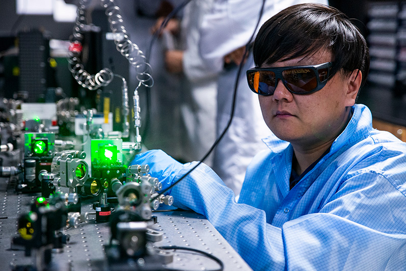 Research fellow Dr Deng Ang from NTU Singapore's School of Electrical and Electronic Engineering calibrating the optical equipment in an experimental set-up with a green laser. The set-up is used to generate intense and ultra-fast mid-infrared lasers. (Credit: NTU Singapore)