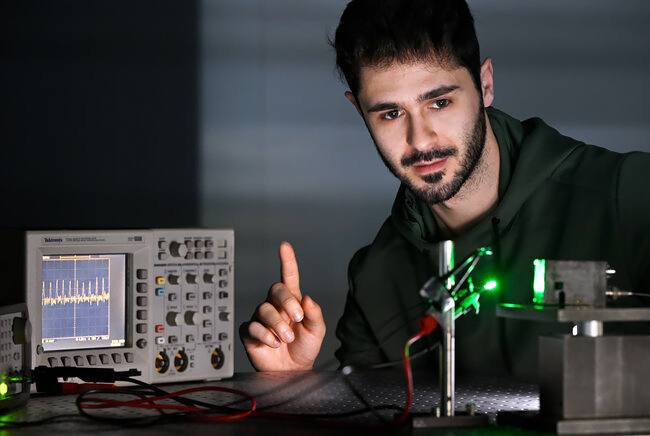 Researcher Riccardo Ollearo shows how the photodiode (right) picks up the signal from his finger, allowing him to see how fast his heart is beating on the screen (left). Photo: Bart van Overbeeke.