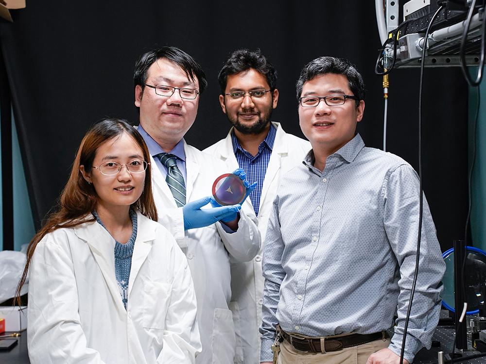 Penn State electrical engineering graduate students (from left) Lidan Zhang, Shengyuan Chang, Md Tarek Rahman and Penn State Associate Professor of Electrical Engineering Xingjie Ni display their flat, compact metalens, which when integrated into a telescope, can image the lunar surface. Credit: Jeff Xu/Penn State. All Rights Reserved.