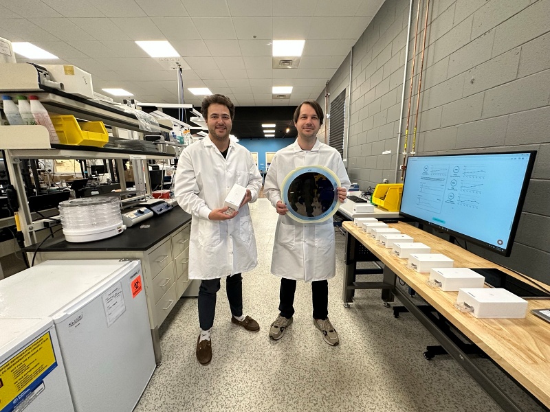 SiPhox Health co-founders Michael Dubrovsky (left) and Diedrik Vermeulen, standing in the SiPhox Health biochip pilot line and laboratory space. CEO Vermeulen is holding a 12-inch diameter silicon photonics wafer featuring SiPhox's sensor chips, while chief product officer Dubrovsky is holding the 