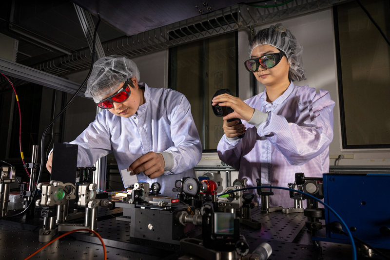 <cap 1>Research Scientists Tong Zhou (left) and Siyun Chen work on the spectral combining of multiple fiber lasers in the Fiber Laser Lab at ATAP. Credit: Paul Mueller/Berkeley Lab.