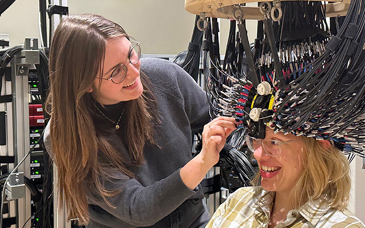 Fogarty adjusts the very high-density diffuse optical tomography (VHD-DOT) cap on labmate Wiete Fehner, ensuring optimal optode coupling and participant comfort as a critical step before data collection. Photo: SPIE.