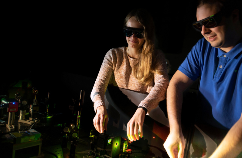 Fiona Cole and Jonas Z&auml;hringer, first authors of the publication, adjusting a fluorescence microscope. &copy; LMU.