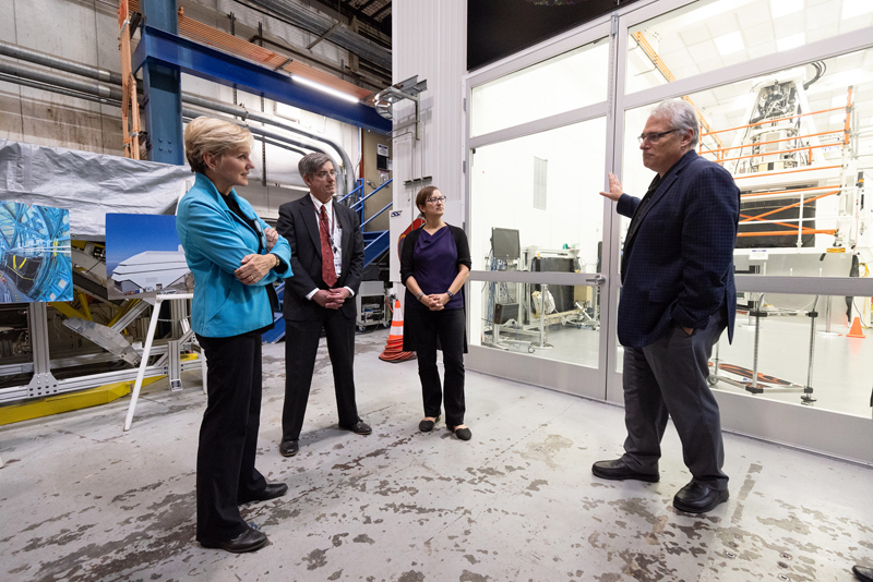 Aaron Roodman, deputy director of Rubin Construction for SLAC and LSST Camera Program Lead, at right, talks to Jennifer M. Granholm, Secretary, U.S. Department of Energy, left, as Granholm visits the Rubin Observatory's Legacy Survey of Space and Time (LSST) Camera under construction at SLAC National Accelerator Laboratory on Thursday, Oct. 26, 2023, in Menlo Park, Calif. SLAC Lab Director John Sarrao and Risa Wechsler, director, Kavli Institute for Particle Astrophysics & Cosmology, are in the background. Photo: Jim Gensheimer/SLAC National Accelerator Laboratory.