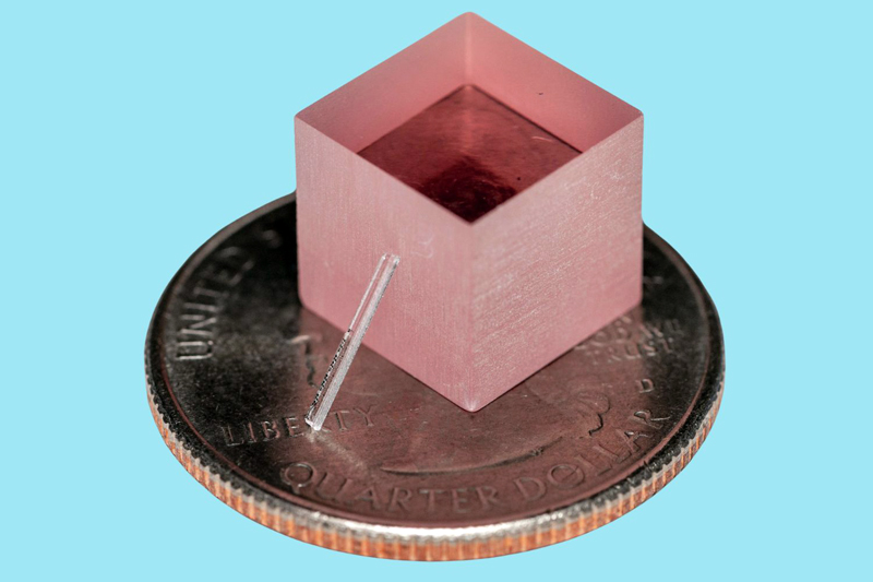 The new laser leans against a block of titanium-sapphire. For scale, both sit atop a quarter. Credit: Yang et al., Nature.