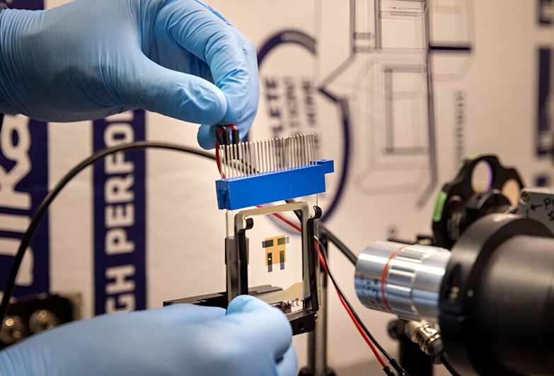 Raju Lampande, postdoctoral researcher in Giebink's lab, positions an OLED that leverages positive feedback to amplify the conversion of near infrared light into visible light in front of a microscope imaging system. Credit: Marcin Szczepanski, Michigan Engineering.