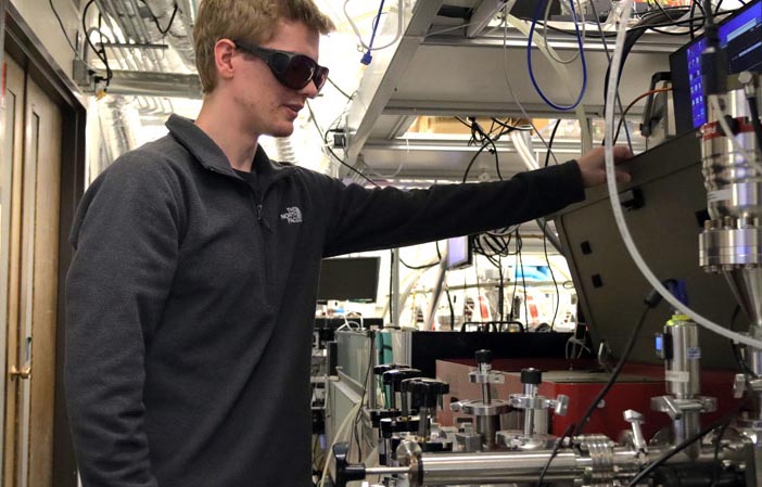 

<cap>Klein, in his lab at JILA, opening the part of the system that upconverts pulsed light from an infrared laser into extreme ultraviolet light through a process known as high harmonic generation. Photo: SPIE.