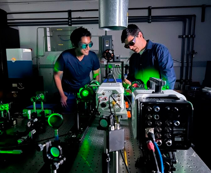 Rishav Choudhary (left), a postdoctoral student in aerospace engineering, looks at a tomographic interferometry optical system with Limbach (right). With funding from the Air Force Office of Scientific Research, Limbach is leading a team that aims to enable satellites to share energy and momentum through laser interlinks. Credit: Jason Bolton, Aerospace Engineering, University of Michigan.