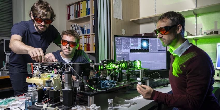 Harald Fitzek, Christian Neuper and Christian Hill (from left) at the sensor platform, which uses laser light to detect nanoplastic particles in liquids. Credit: Lunghammer - TU Graz.