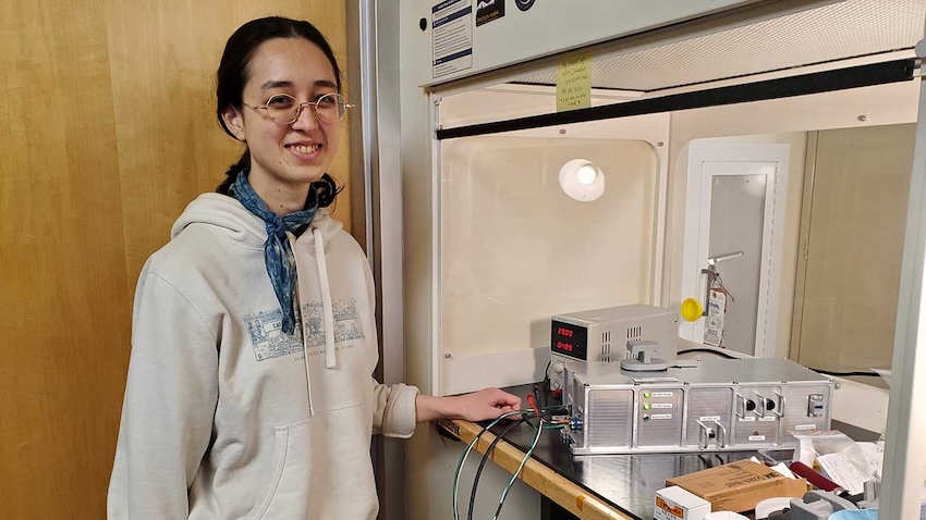 Nikki Johnston, a Ph.D. student at Portland State University, stands next to the Extant Life Volumetric Imaging System (ELVIS). This innovative system aims to advance how we study cellular processes in space. Credit: Jay Nadeau.