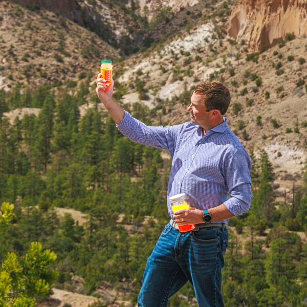 UbiQD founder and CEO Hunter McDaniel, pictured with jars of the New Mexico firm's quantum-dot materials. Aimed at applications across greenhouse agriculture, solar windows, and security, McDaniel has said previously that the cadmium-free QDs, based around copper indium sulfide, offer a low-cost and low-toxicity alternative to the cadmium selenide and indium phosphide QDs typically found in display applications. Just 1.5 kg of the QD material is said to be enough to cover an area of 5000 ft<sup>2</sup>. Photo: UbiQD.