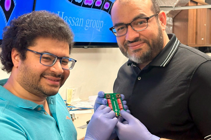 Mohammed Hassan (right), associate professor of physics and optical sciences, and Mohamed Sennary, a graduate student studying optics and physics, holding the commercial transistor they used to develop a petahertz-speed transistor. Photo courtesy of Mohammed Hassan, U. Arizona.