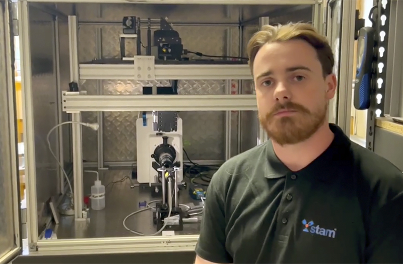 Leo Devlin, from Trinity's School of Engineering, with the LAPAO machine. The LAPAO was built by Trinity's Science & Technology in Advanced Manufacturing (STAM) research group. It uses a laser to fire particles of 10-60 microns in size at speeds of up to 1 km per second. Credit: Trinity College Dublin.</p>
