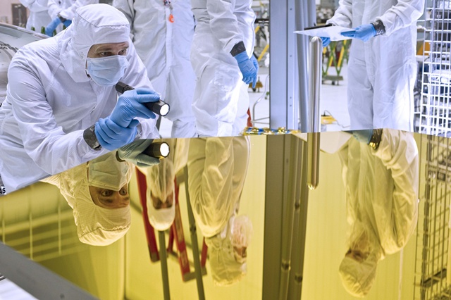 An engineer examines the Webb telescope primary mirror Engineering Design Unit segment in the clean room at NASA's Goddard Space Flight Center, Greenbelt, Md. Credit: NASA/Chris Gunn.