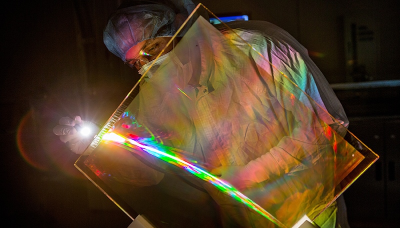 Marcus Monticelli inspects the anti-reflective coating on a National Ignition Facility grating debris shield. The coating restores lost NIF energy and eliminates a source of optics damage. Photo by Jason Laurea/LLNL