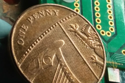 Chip containing all the optical components used to generate quantum-based random numbers at high speed. Here the chip, at the bottom-right corner of the picture, is placed next to a penny coin for comparison. Image: Francesco Raffaelli, University of Bristol.