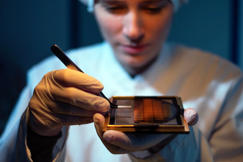 A Q.ANT employee inspecting a quantum chip.