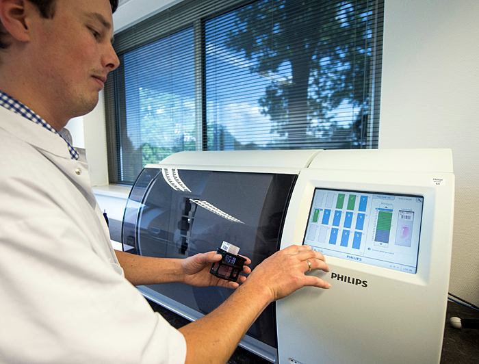 Quick turnaround: a technician inserts tissue slides into Philips IntelliSite ultra-fast scanner.
