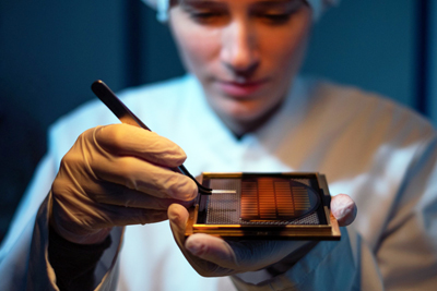 A Q.ANT employee inspecting a quantum chip.